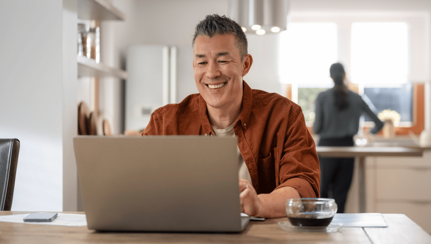 A man smiling while using the patient portal on a laptop at home