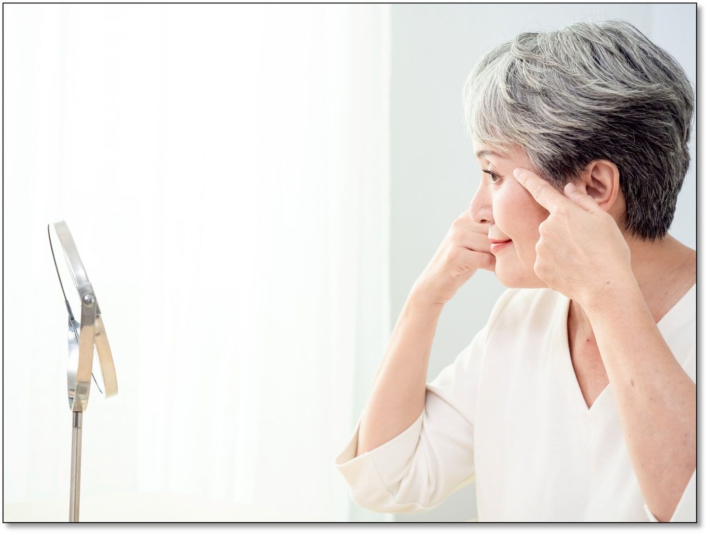 older woman looking in mirror contemplating BOTOX for fine lines framed