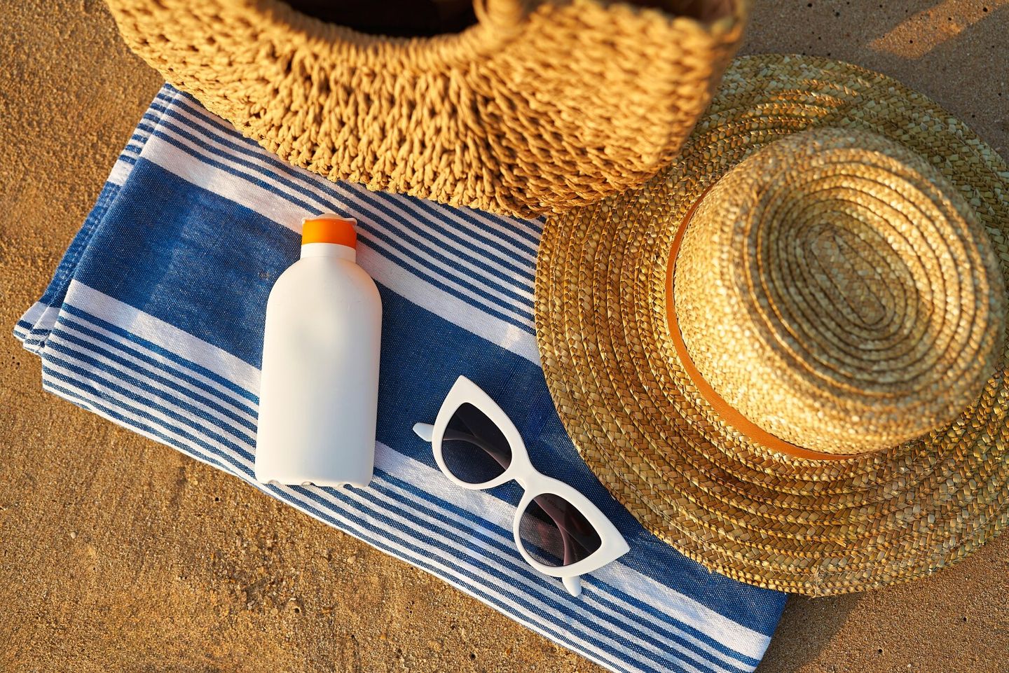 sun-hat-sun-screen-and-sunglasses-on-beach-towel-in-shade