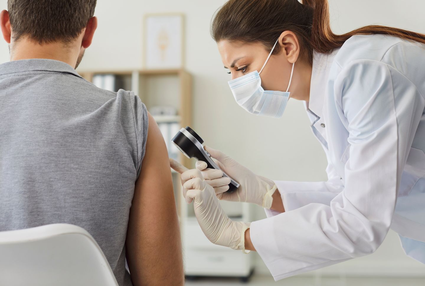 Female doctor examining hand skin of young man patient for ringworm