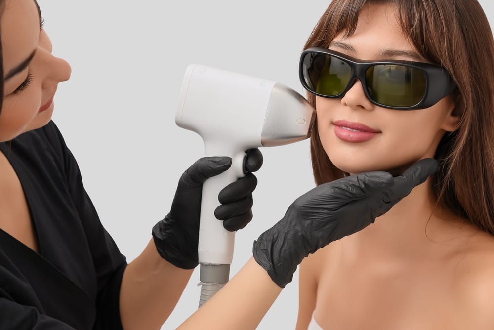Female cosmetologist performing photoepilation on client's face in beauty salon, closeup
