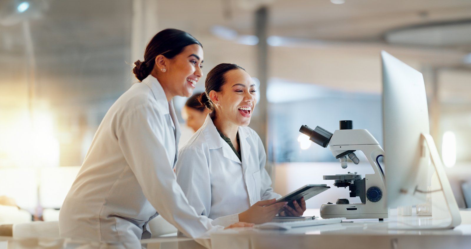 Two lab clinicians collaborating at a microscope