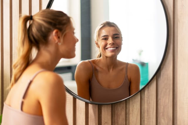 woman looking in mirror body positivity