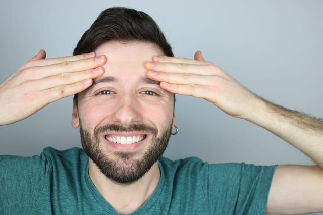 Happy young man feeling face after neurotoxin botox treatment